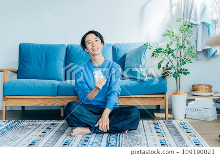 Young man relaxing in the living room, smartphone 109190021