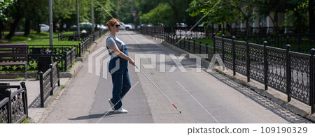 Blind pregnant woman crosses the street with the help of a tactile cane. 109190329