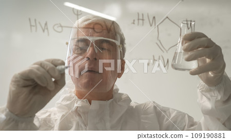 An elderly Caucasian male chemist in a protective suit writes on glass. An elderly Caucasian male chemist in a protective suit writes on glass. 109190881