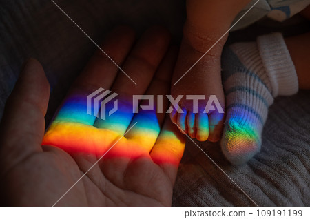 A man holds his newborn son by the leg. Beam of light through a prism. A man holds his newborn son by the leg. Beam of light through a prism. 109191199