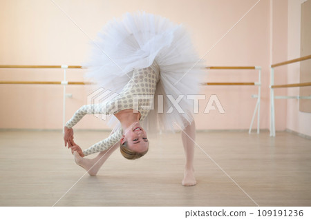 Beautiful ballerina is training in a dance class. Young flexible dancer posing in pointe shoes. A woman in a body and a white tutu dances a classical dance. Beautiful ballerina is training in a dance class. Young flexible dancer posing in pointe shoes. A woman in a body and a white tutu dances a classical dance. 109191236