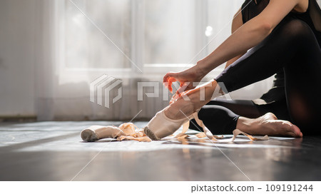 Faceless ballerina sits on the floor and puts on pointe shoes. Faceless ballerina sits on the floor and puts on pointe shoes. 109191244