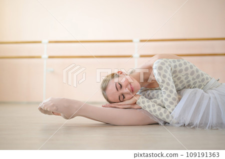 Beautiful ballerina is training in a dance class. Young flexible dancer posing in pointe shoes. A woman in a body and a white tutu dances a classical dance. 109191363