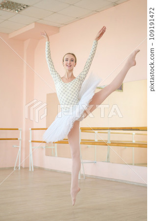 Beautiful ballerina in body and white tutu is training in a dance class. Young flexible dancer posing in pointe shoes. Beautiful ballerina in body and white tutu is training in a dance class. Young flexible dancer posing in pointe shoes. 109191472