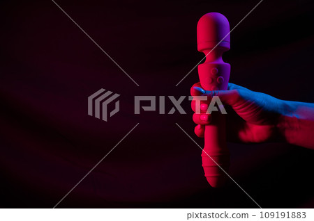 Woman holding a vibrator in neon pink and blue light. 109191883