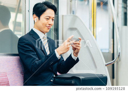 一位中年商人在上下班時看著智慧型手機。照片由京王電鐵株式會社提供。 109193128