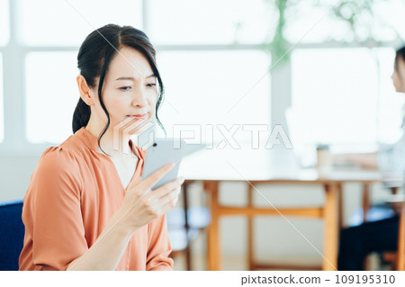 一名中年婦女在咖啡館使用智慧型手機。 一名中年婦女在咖啡館使用智慧型手機。 109195310