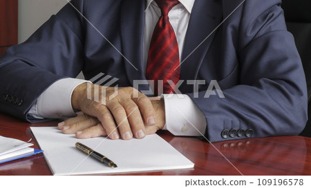 Businessman at desk with hands folded 109196578