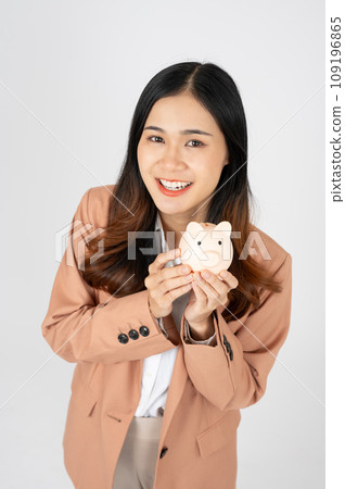Cheerful Asian businesswoman holding piggy bank isolated on white background Cheerful Asian businesswoman holding piggy bank isolated on white background 109196865