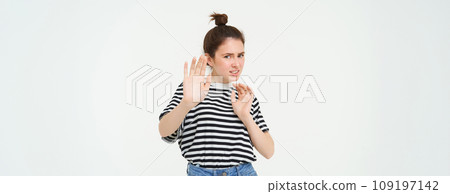 Disgusted woman steps back, raising hands defensive, avoiding something, rejecting and refusing offer, standing over white background Disgusted woman steps back, raising hands defensive, avoiding something, rejecting and refusing offer, standing over white background 109197142