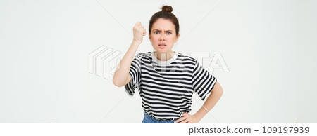 Image of angry woman threatening, shaking fist with disapproval, scolding someone, standing over white background 109197939