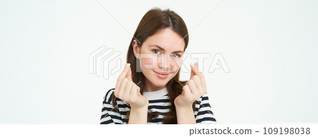 Portrait of cute young brunette woman, shows kawaii finger hearts and smiling, likes smth, stands in striped t-shirt over white background Portrait of cute young brunette woman, shows kawaii finger hearts and smiling, likes smth, stands in striped t-shirt over white background 109198038