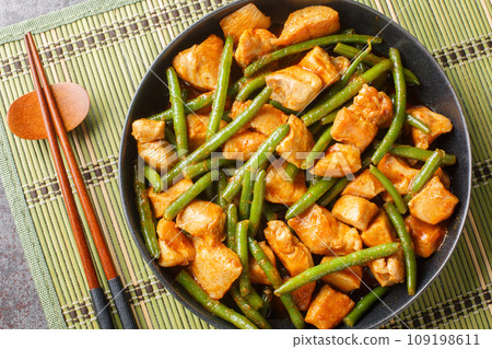 Pad prik king is a Thai stir-fried dish featuring chicken meat, stir-fried with red curry paste, long beans, and sometimes kaffir lime leaves closeup. Horizontal top view Pad prik king is a Thai stir-fried dish featuring chicken meat, stir-fried with red curry paste, long beans, and sometimes kaffir lime leaves closeup. Horizontal top view 109198611