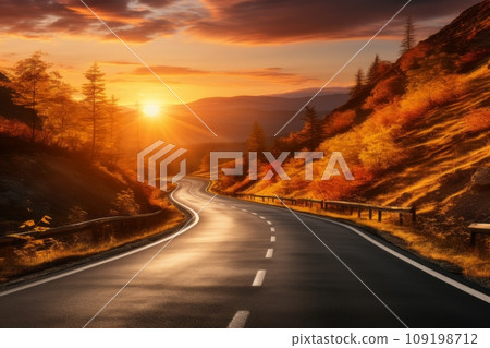 Endless asphalt road and majestic mountains are bathed in golden glow at sunset. 109198712