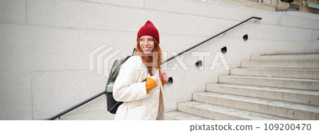 Happy young girl, redhead tourist in red hat with backpack, walks around town, explores city, backpacking around europe, travelling alone Happy young girl, redhead tourist in red hat with backpack, walks around town, explores city, backpacking around europe, travelling alone 109200470