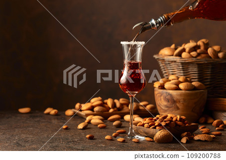 Italian liqueur Amaretto with almonds nuts on a wintage table. Italian liqueur Amaretto with almonds nuts on a wintage table. 109200788