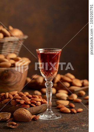 Italian liqueur Amaretto with almonds nuts on a brown background. Italian liqueur Amaretto with almonds nuts on a brown background. 109200791