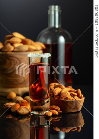 Italian liqueur Amaretto with almonds nuts on a black background. 109200803