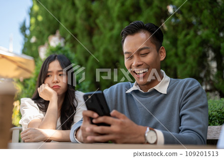 Young Asian girlfriend getting upset at her boyfriend for not paying attention to her. Young Asian girlfriend getting upset at her boyfriend for not paying attention to her. 109201513