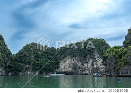 Vietnam: A person rows a kayak in Halong Bay, which is surrounded by strangely shaped rocks, and arrives at a tourist spot. 109201668