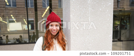 Beautiful redhead girl with smartphone, standing on street, holding mobile phone, using taxi app, connects to public wifi and uses internet, sends a text message 109201751