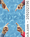 2024, People pointing to the number 2024 on background of faded lights. Happy New Year 109202396