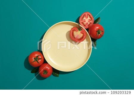 Advertising scene with minimal concept. Fresh ripe tomatoes decorated with a round yellow ceramic dish on a green background. Salad preparation ingredients. Empty copy space for mockup 109203329