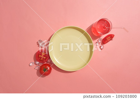 A round dish in yellow color displayed with some tomato slices, ices and a glass of tomato juice. Vacant space on the dish to show cosmetic product of Tomato extract A round dish in yellow color displayed with some tomato slices, ices and a glass of tomato juice. Vacant space on the dish to show cosmetic product of Tomato extract 109203800