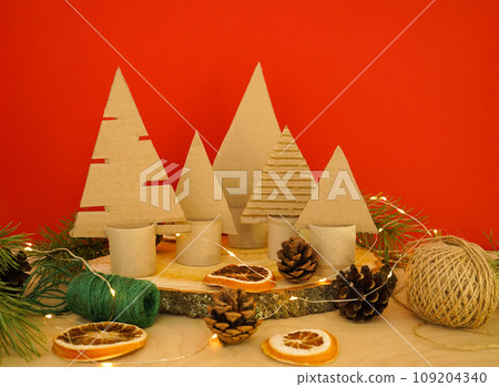 A creative handmade little Christmas tree of cardboard on red backround. eco-friendly and zero waste concept A creative handmade little Christmas tree of cardboard on red backround. eco-friendly and zero waste concept 109204340