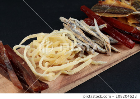 Wooden tray with snacks. Beer set. Dried fish, fish straws, salted squid. Close-up. 109204628
