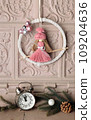 New Year's home decor. Interior design. A wreath on the fireplace, a vintage clock and fir branches. 109204636