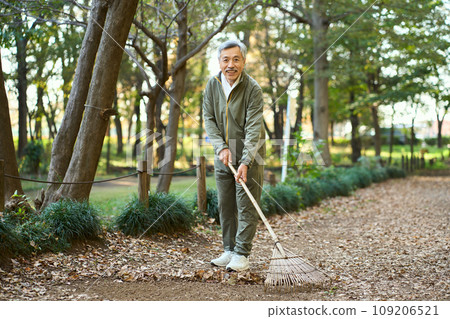 一名男子用耙子耙落葉 109206521