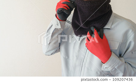 A man in work clothes protects himself from the cold with a neck warmer 109207436
