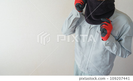 A man in work clothes protects himself from the cold with a neck warmer 109207441