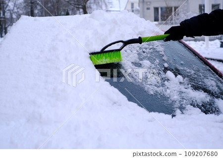 Snow cleaning from car with a brush in close-up Snow cleaning from car with a brush in close-up 109207680