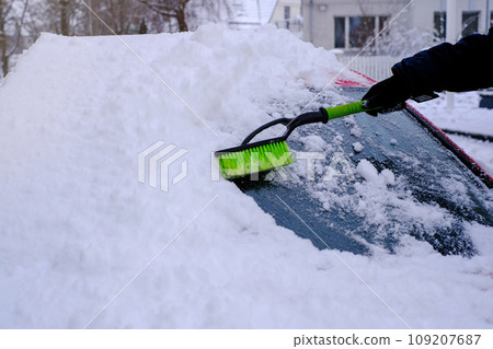 Snow cleaning from car with a brush in close-up 109207687