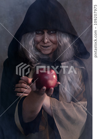 Stepmother witch gives poisoned red apple.Woman as witch in black offers red apple as symbol of temptation, poison. Fairy tale, white snow wizard concept. Spooky Halloween, cosplay. Stepmother witch gives poisoned red apple.Woman as witch in black offers red apple as symbol of temptation, poison. Fairy tale, white snow wizard concept. Spooky Halloween, cosplay. 109207975