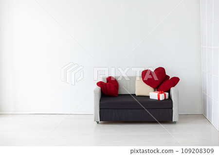A sofa with a heart-shaped pillow and gifts in a bright room 109208309