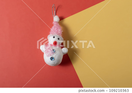 Christmas snowman toy on red and yellow background with copy space for text. 109210363