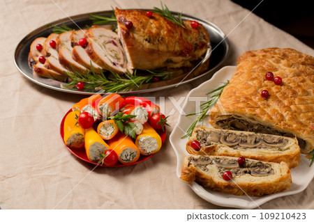 Traditional festive Christmas dishes on the table. Wellington with mushrooms, stuffed turkey roll 109210423