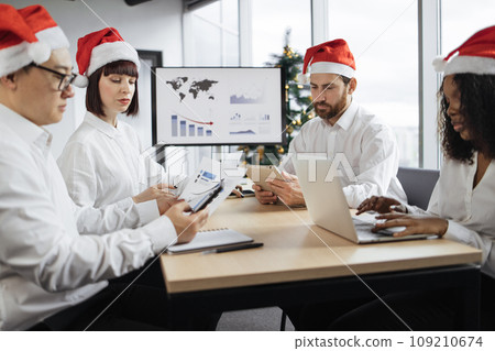 Multiethnic diverse business colleagues in Santa hats at meeting in office 109210674