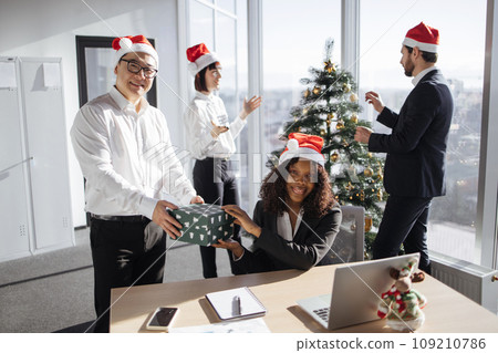 Smiling diverse colleagues exchanging christmas gifts at corporate party Smiling diverse colleagues exchanging christmas gifts at corporate party 109210786