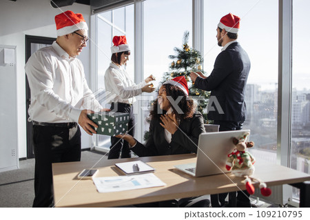 Asian and African american colleagues exchanging xmas gift box in festive office 109210795