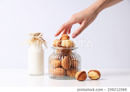 Nuts cookies in a glass jar with a bottle of milk Nuts cookies in a glass jar with a bottle of milk 109212066