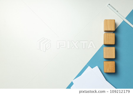 Wooden cubes, papers and pen on white and blue background, space for text Wooden cubes, papers and pen on white and blue background, space for text 109212179