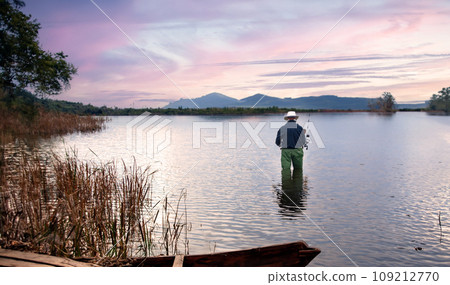 pond landscape in twilight with fisherman fishing on water in vocation day 109212770