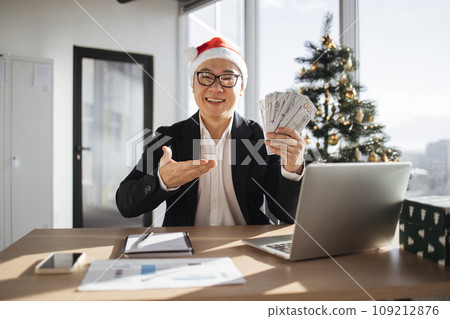 Asian attractive man in Santa hat pointing on hand with cash papers 109212876