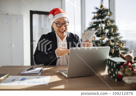 Asian attractive man in Santa hat lifting hands with cash papers 109212879