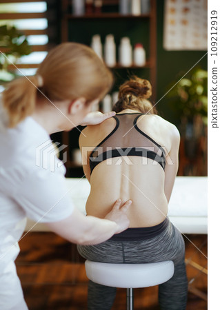 medical massage therapist checking clients back condition 109212919