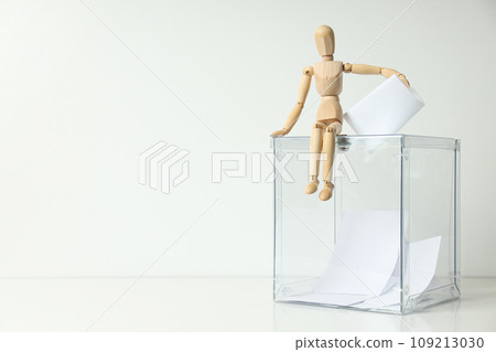 Voting box with papers and wooden man on white background, space for text 109213030